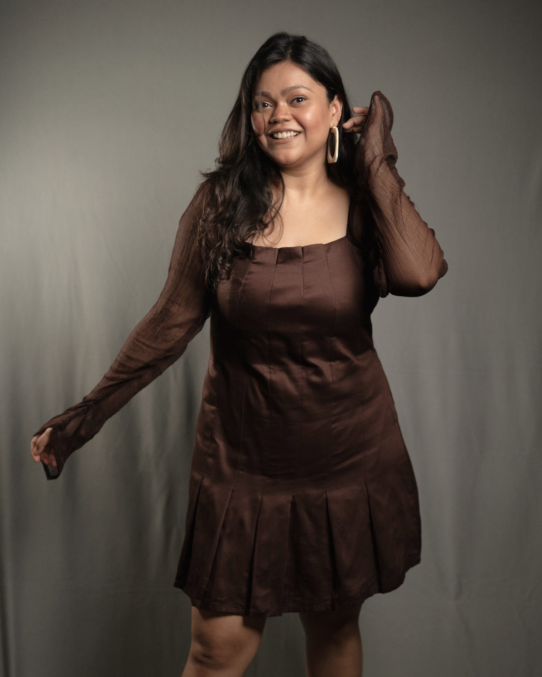 Deep brown pleated dress with a square neckline and sheer sleeves, designed for an elegant and flattering silhouette.