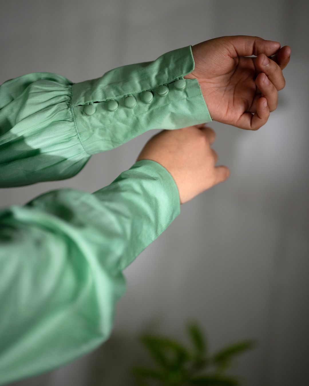 Green Aurora Tie-Up Top featuring a V neckline, bishop sleeves cinched at the wrists, and a playful tie-up detail at the back